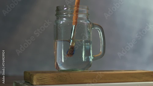 Cleaning water color paint brushes in jar of water