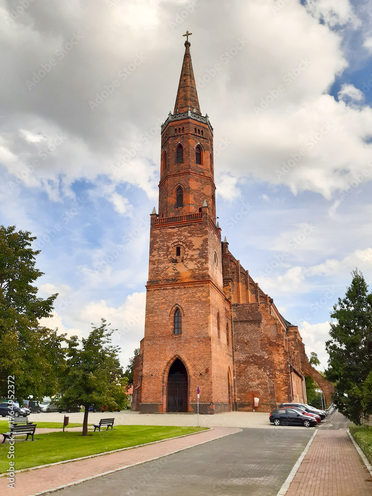 Obraz premium Majestic brick church in Glogow, Poland spire against dramatic cloudy sky