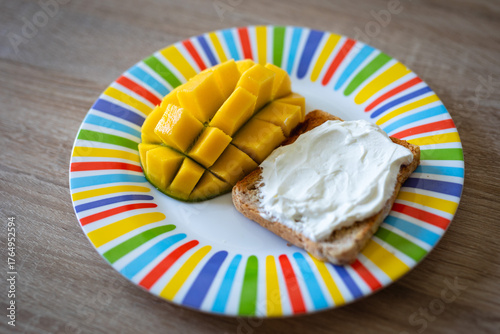 Deliciously fresh mango slices and creamy spread on toast served on a vibrant striped plate, perfect for a healthy breakfast or snack.