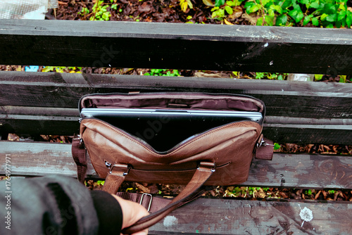 Brown leather bag with laptop left unattended in a park during the afternoon