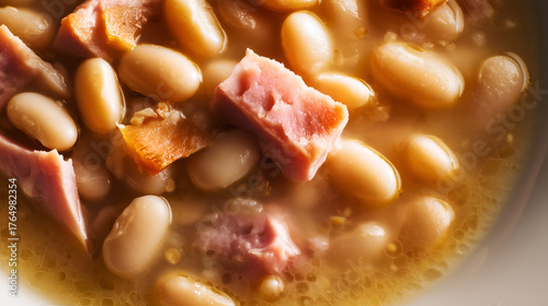 Plump beans and oily sheen evoke clarity, ritual, and editorial depth in culinary storytelling. Pink ham and broth texture highlight warmth, protein, and comfort rhythm.