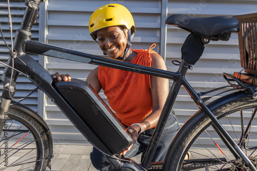 Young African Woman changing battery on her electric bicycle