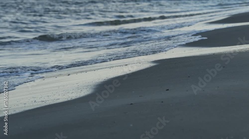 Golden sunset light bathes the northern Danish coast, where shorebreak waves meet a wide sandy beach