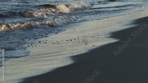 Golden sunset light bathes the northern Danish coast, where shorebreak waves meet a wide sandy beach