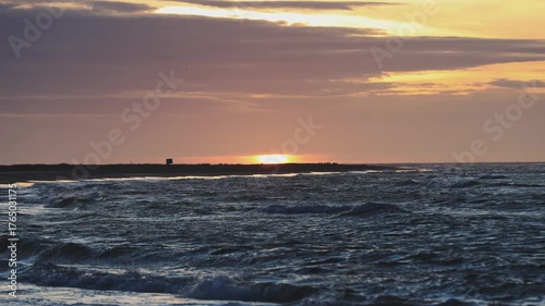 Golden sunset light bathes the northern Danish coast, where shorebreak waves meet a wide sandy beach