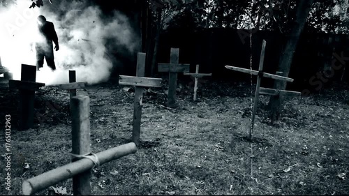 A zombie walking through a rustic cemetery graveyard with crosses and smoke. Classic suspense horror or Halloween film theme. Edited with vintage silent film effects.