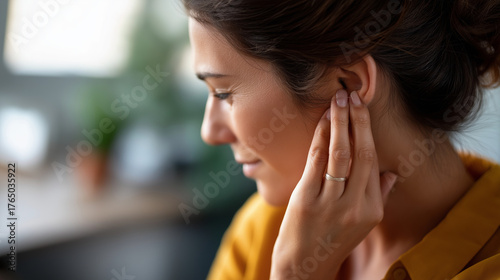 Woman's hand touching painful ear face partially visible ear pain otitis hearing discomfort ear infection tinnitus auditory problem medical concern home interior