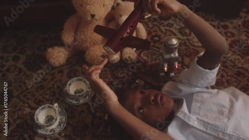 A young boy relaxes on a floor rug surrounded by his favorite toys
