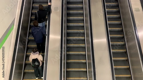 Big city concept, underground escalator with people. People are riding an escalator in an underground metro passage.