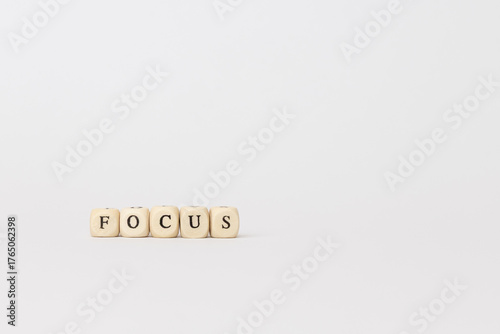 Wooden blocks spelling the word focus on a minimalistic background, representing clarity, concentration, and mindfulness in daily life. copy space