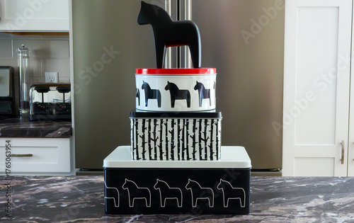 A black wooden Dala horse toy stand on top of tin containers on the counter top. Swedish traditional theme concept.