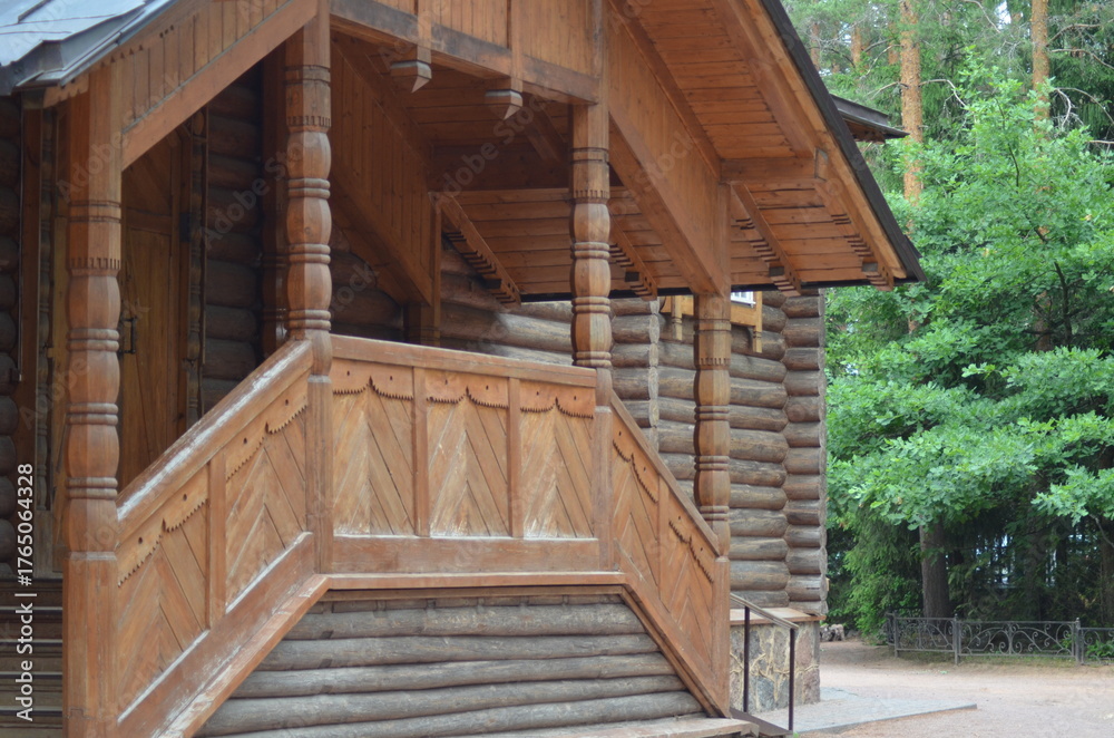 Fototapeta premium The porch of an Orthodox church. A wooden church stands among the pine trees on the site. The frame, doors, windows, walls, steps, and all the details are made of wood. The yellow wood has darkened.