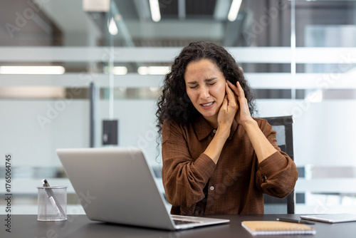 Papier peint Young woman at her office desk clutching her ear in pain, wincing from earache o