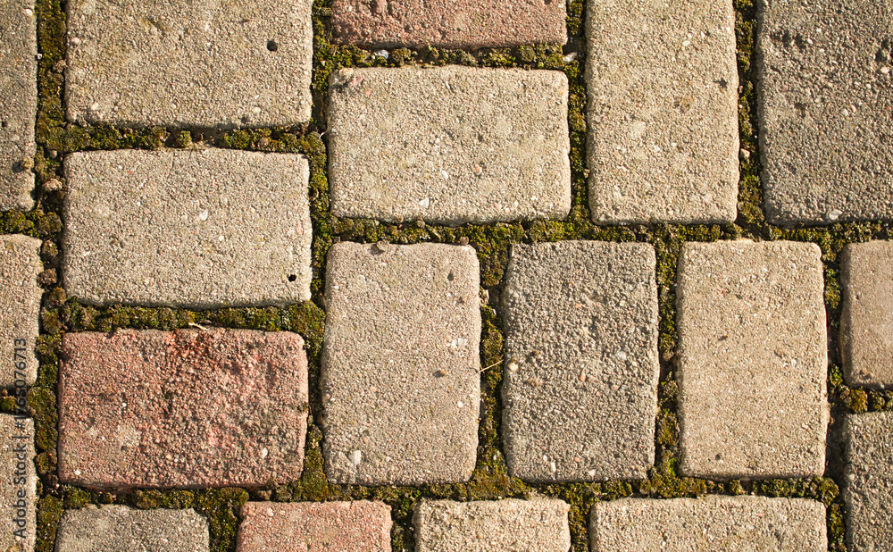 Obraz premium An ancient road made of cobblestones and moss, background, texture. An ancient road. A path made of bricks covered with mold.