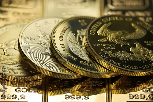 4 different 1 ounce gold bullion coins on a layer of gold ingots
