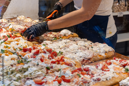 Fresh baked focaccia or pala romana pizza with vegetables, pepperone, mushrooms, tomatoes and cheese in bakery in Parma, Emilia Romania, Italy