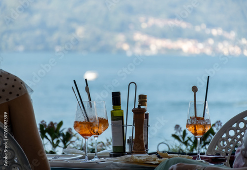 Fototapeta Naklejka Na Ścianę i Meble -  Drinks on Como lake near Milan, tasting of traditional italian cocktail with sparkling wine Prosecco, orange, aperol or campari bitter liquor in bar with view on waters of Como lake, Italy