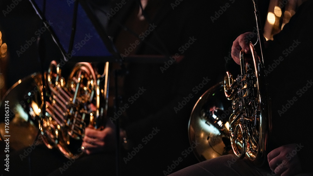 Fototapeta premium Close up of orchestra brass section featuring french horn and trumpet with golden reflections and bokeh lights in dark moody background