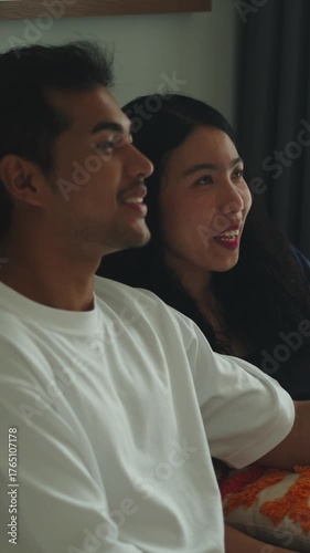 Young happy couple watching television at home