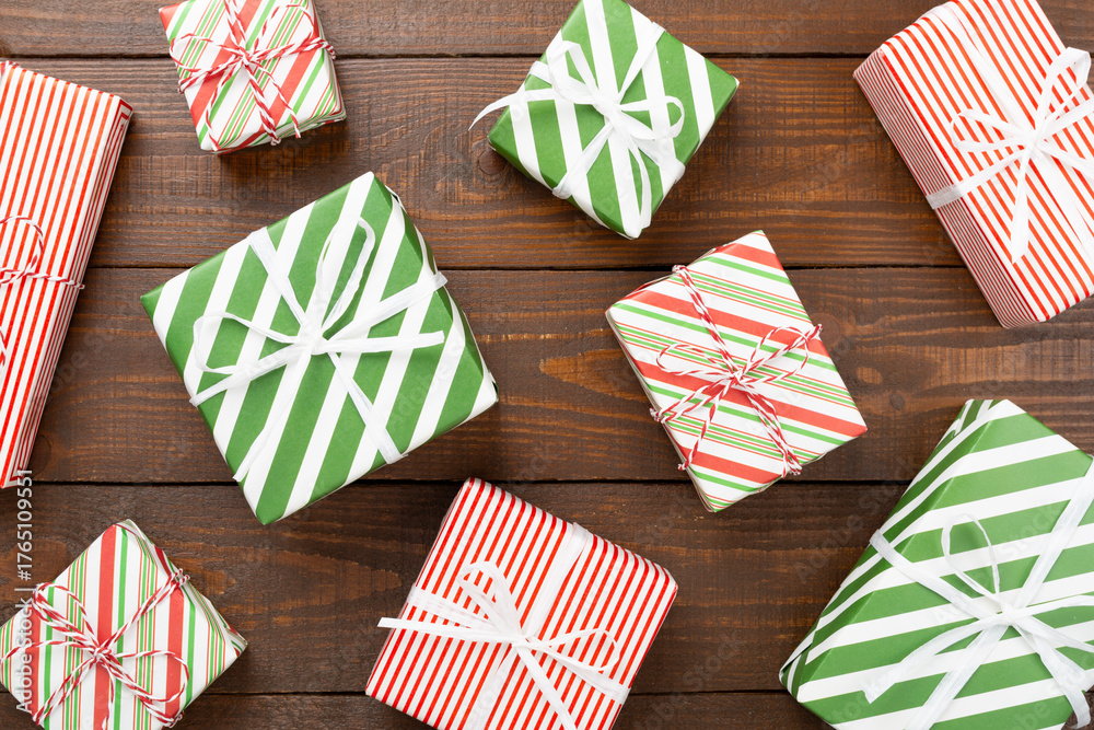 Obraz premium Many striped Christmas gift boxes on wooden background, top view