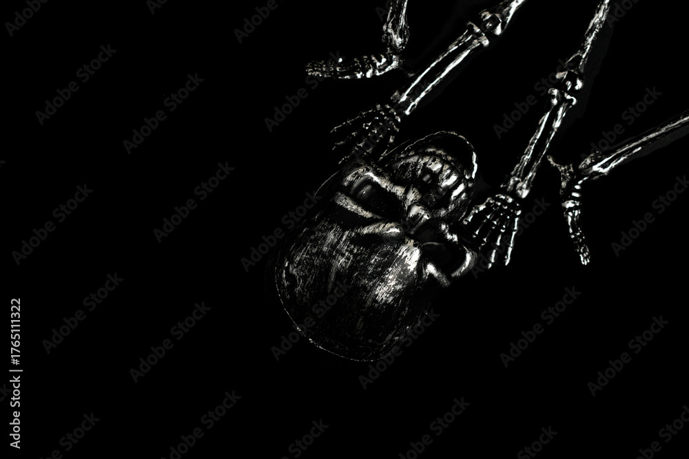 Obraz premium Grungy Silver Skeleton Lying on a Pure Black Background in Low Key Lighting for Halloween Horror, Death and Mystery Concept