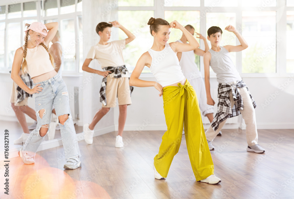 Naklejka premium Active teenagers practicing hip-hop dance in training hall during group dancing classes