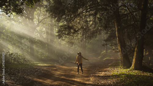 Asian woman traveler is happy with the scenic dirt road through a dense mountain pine forest in San Pa Kia Mt., Chiang Dao, Chiang Mai, Thailand.