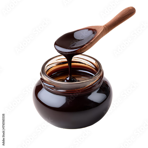 Rich dark molasses dripping from a wooden spoon into a jar