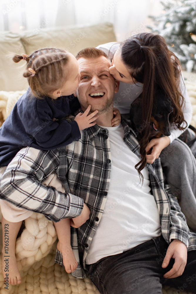 Obraz premium A happy family shares a moment of affection, with a daughter and wife kissing the father.