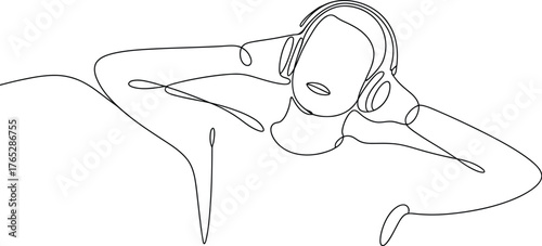 A person with headphones lies down, listening to music.
