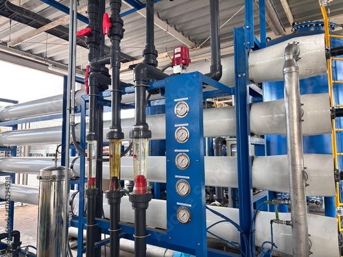 Industrial water treatment machinery featuring multiple horizontal Reverse Osmosis (RO) membrane vessels or filter housings. The system includes a blue control panel with pressure gauges and black PVC