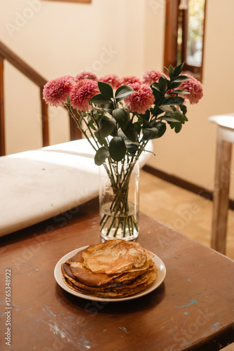 Thin pancakes against the background of surf boards and vases of flowers. Beautifully serving  a delicious breakfast with crepes in the living room