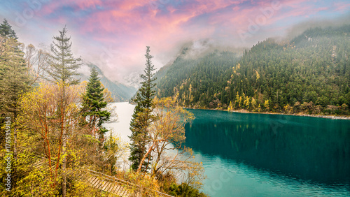 Serene turquoise water beneath mist-covered mountains and autumn forest in Jiuzhaigou National Park, Sichuan, China, capturing tranquil scenery, travel inspiration, and unspoiled wilderness charm.