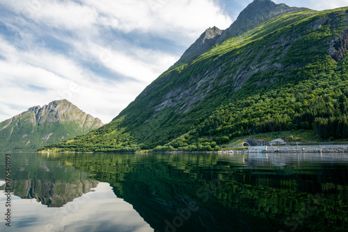 Calm water in a fjord where the mountains are reflected in the water.