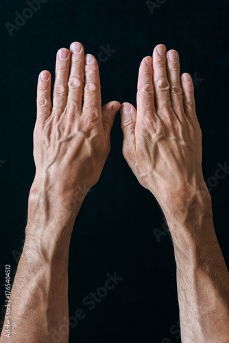 Fotografie Muscular male hands with blood veins on black background