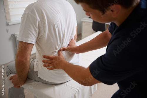 Chiropractor performing manual back adjustment on patient in medical clinic. Physiotherapy, spinal alignment, and rehabilitation treatment for lower back pain relief.
