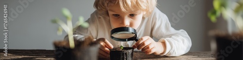 A charming and inquisitive close-up shot of a young boy examining a small seedling with a magnifying glass