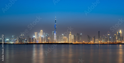 Dubai skyline glows at twilight over calm waters
