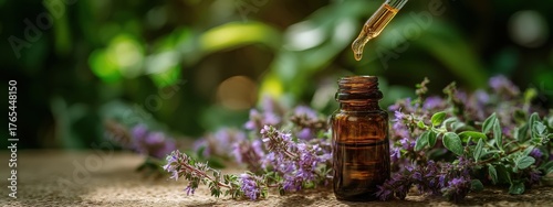 A drop of thyme essential oil falling from a dropper into a bottle among flowers