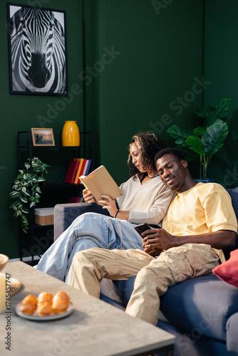 Young couple relaxing at home, reading and using phone