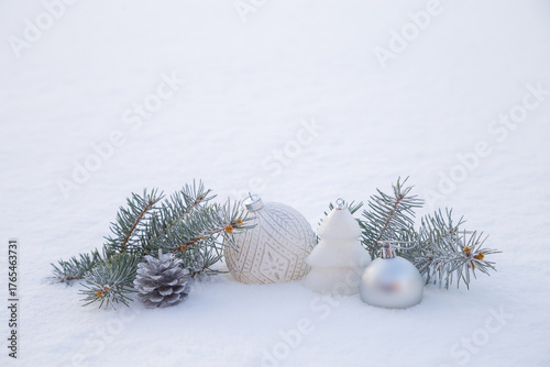 Christmas decorations and fir branches in fluffy snow. Copy space.