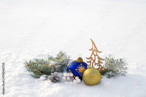 Christmas decorations and fir branches in fluffy snow. Copy space