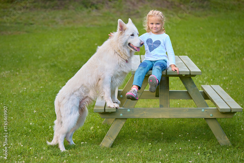 Four years old girl portrayed with her swiss white shepherd friend