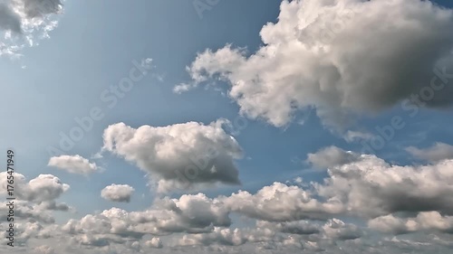 Clouds fly to the right in the blue skies. 4K video (Ultra High Definition) of cloudscape. Sky and clouds Timelapse. Sun shines through the clouds on the blue sky background.