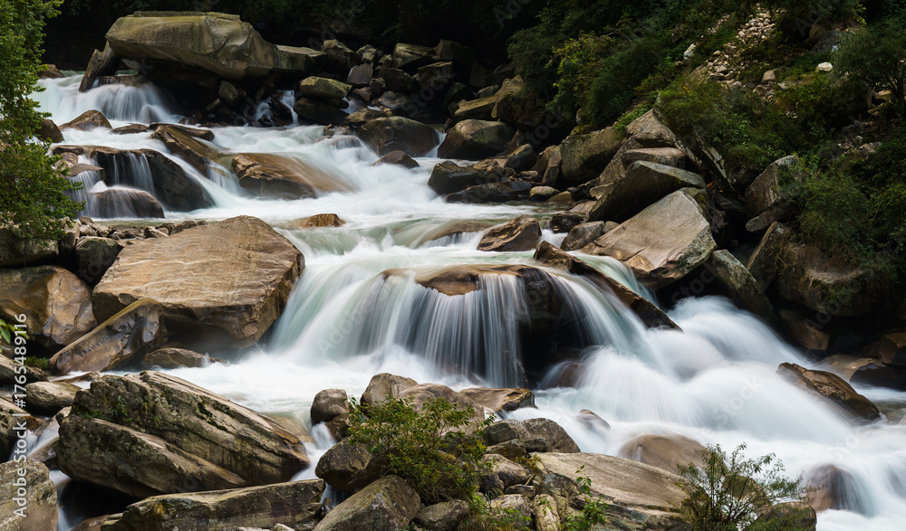 Fototapeta premium Cascading water flows over smooth river stones