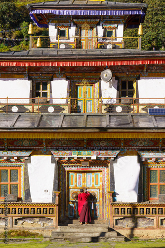 Monk approaches ornate colorful temple doors