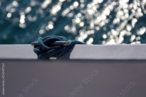 Close-up view nautical rope secured on cleat against blue sea. Rope is fixed to side of yacht.  Copy space. Selective focus.