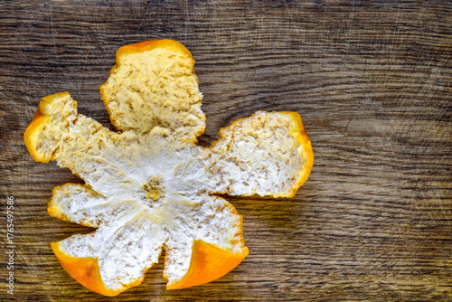 Mandarin peel in form of flower on old oak board. Close-up. Copy space. Top view
