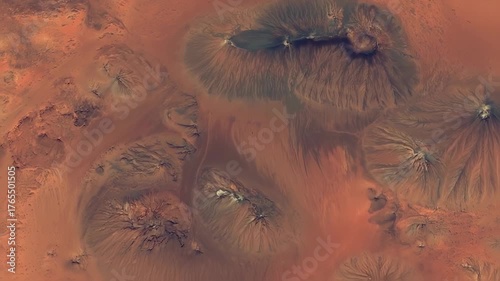 Aerial view of a barren, reddish landscape with multiple formations resembling water-eroded structures