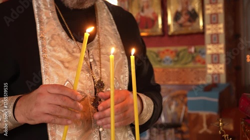 Close-up of a priest lighting candles during an Orthodox church service. The warm glow and sacred atmosphere symbolize faith, prayer, and divine blessing.
